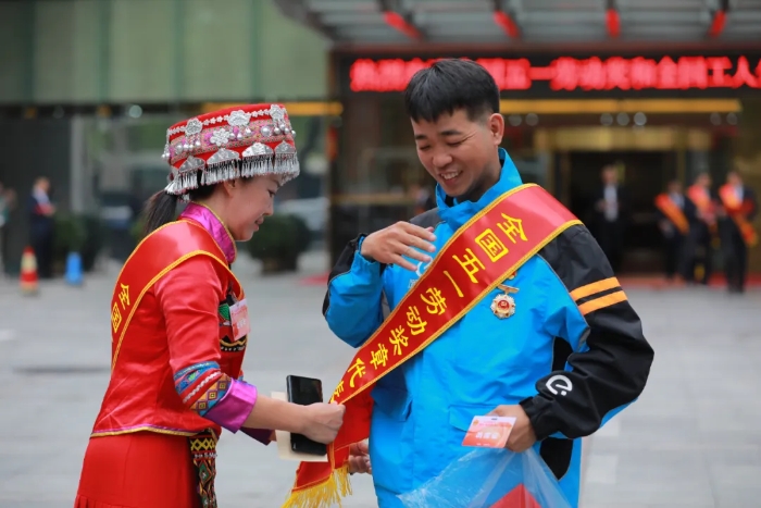 在中国职工之家门口，今年的全国五一劳动奖章获得者粟琼(图左)帮助另一位获奖者洪成木整理绶带。